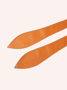 Macro view of orange leather belt ends featuring fine texture and precision edge stitching