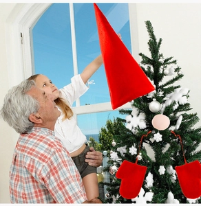 Close-up of red plush Santa hat and gloves set decorating a festive Christmas tree
