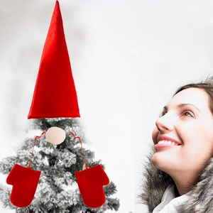 Detail of red plush gnome Christmas tree topper set with hat and gloves on branch