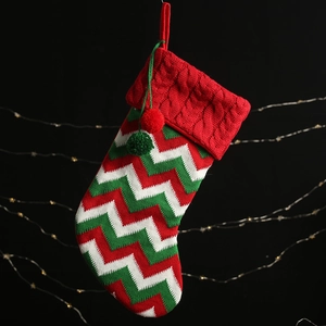 Knitted Christmas stocking with red and green chevron patterns and fluffy pom-pom charms