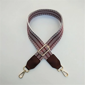 Detail of adjustable wine red and white geometric embroidered strap with gold buckles
