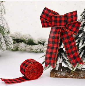Detail of red and black buffalo plaid ribbon roll and decorative bow on a snowy Christmas tree