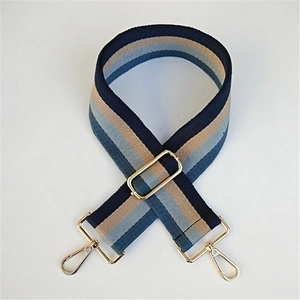 Detail of adjustable blue and beige striped bag strap with gold metal hooks and buckle