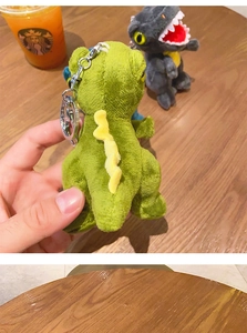 Detail of plush dinosaur keychains in green and grey with silver lobster clasps