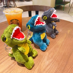 Three colorful plush dinosaur keychains with metal rings on a wooden table surface