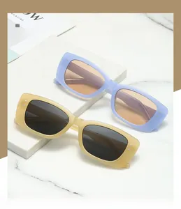 Detail of rectangular Y2K sunglasses with rivet accents on white marble surface