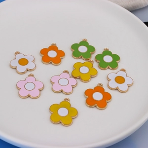 Detail of colorful alloy sunflower charms in a white ceramic dish for DIY jewelry