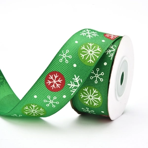 Macro view of green Christmas ribbon with white snowflake prints and gold foil details