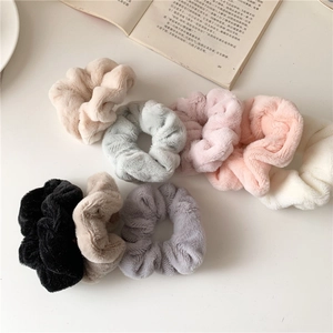 Close-up of soft faux fur scrunchies in assorted Morandi colors on a book