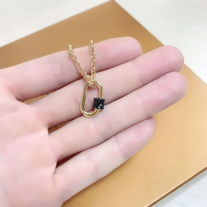 Chunky gold chain necklace with black pave carabiner pendant held in hand for size