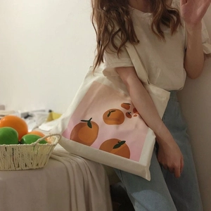 Canvas tote bag with orange graphic print shown on a model in a warm lifestyle setting