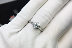 Close-up of a classic six-prong moissanite diamond ring on a gloved hand with fire details