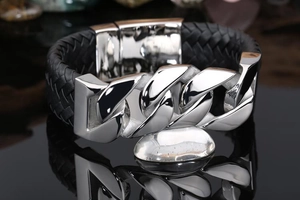 Macro detail of men's wide leather braided bracelet with polished Cuban chain links