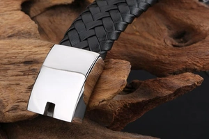 Macro shot of polished silver metal clasp and black woven leather texture of the men's bracelet