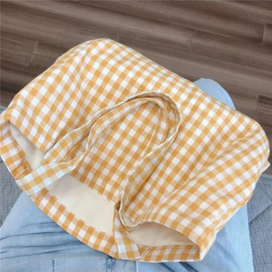 Close-up of a yellow and white gingham canvas tote bag held over blue jeans
