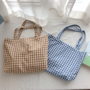 Detail of blue and brown checkered cotton tote bags on a minimalist soft white background