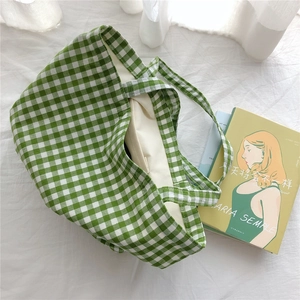 Detail of green and white gingham cotton tote bag with double handles on a soft background