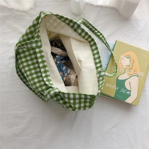 Close-up of green gingham cotton tote bag interior capacity with books and floral pouch