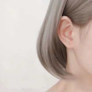 Close-up of three minimalist S999 sterling silver stud earrings worn on a female ear