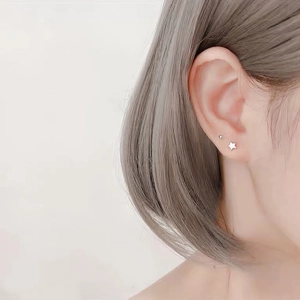 Macro shot of minimalist S999 sterling silver star and ball studs worn on ear