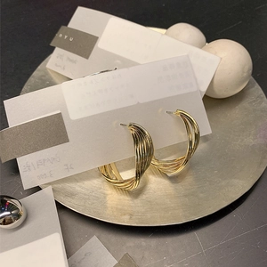 Close-up of gold geometric twisted hoop earrings displayed on an artistic silver tray