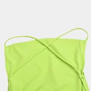 Detailed view of green backless dress with thin crossover straps and smooth fabric