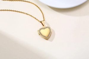 Detail of gold heart locket necklace with sparkling rhinestones and delicate chain