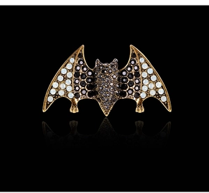 Macro detail of bat brooch with gold finish and inlaid black and white rhinestones