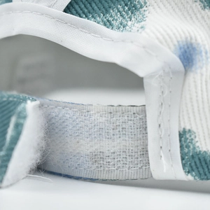 Macro detail of adjustable Velcro strap on tie-dye cotton sun hat with ribbed texture