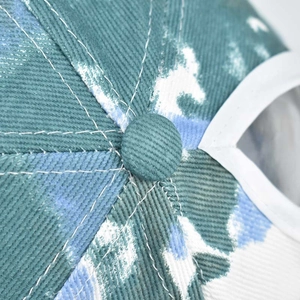 Macro detail of high-density cotton tie-dye baseball cap top button and stitched panels