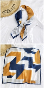 Detail of elegant geometric satin square scarf tied on a white collar with flat layout