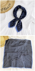 Detail of navy blue square silk scarf with geometric patterns and knotted necktie look