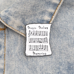Détail d'une broche en émail partition de musique sur un col en denim