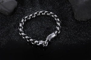 Braided black leather bracelet with silver steel rings on black crystal sand rocks