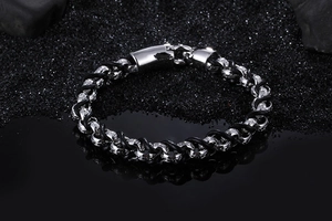 Detail of men's black leather braid bracelet with interlocking silver steel rings