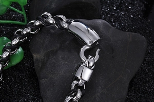 Close-up of men's stainless steel links and black braided leather bracelet on dark rock
