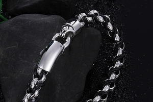 Close-up of men's stainless steel interlocking ring bracelet with black braided leather strap