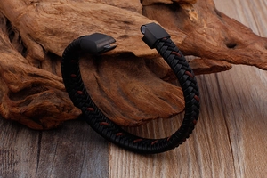 Gros plan sur le bracelet en cuir tressé noir avec fermoir magnétique sur bois