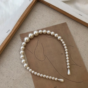 Detail of elegant pearl headband featuring gradient sizes and teardrop pearl ends