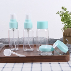 7-piece travel set with transparent spray bottles and mint green lids on a wooden tray