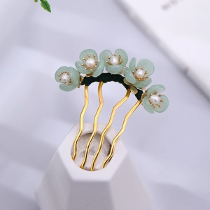Close-up of green flower hair pin with pearl center and golden U-shaped frame