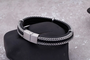 Detail of multi-layer black leather braid bracelet with silver wheat chain and magnetic clasp