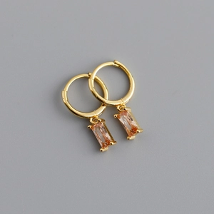 Gros plan de créoles dorées avec d'élégants pendentifs rectangulaires en cristal champagne