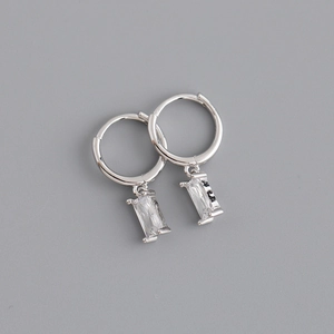 Détail de boucles d'oreilles créoles argentées avec pendentifs rectangulaires en zircon