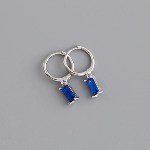 Détail de créoles argentées avec pendentifs en pierres précieuses rectangulaires bleues