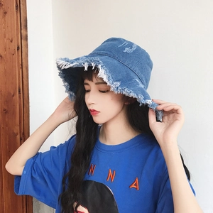 Detail of frayed fringe edges and distressed texture on a dark blue denim bucket hat