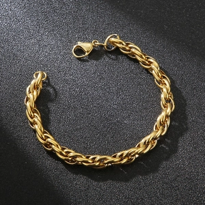 Macro shot of gold woven chain bracelet with lobster clasp on dark textured background