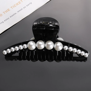 Elegant black hair claw clip with gradient pearls shown on reflective dark background