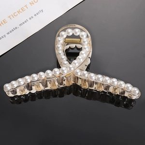 Elegant champagne acrylic hair claw clip with white pearls on a reflective black background