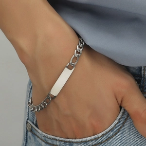 Men's silver Figaro chain bracelet with blank ID plate worn on wrist with denim jeans